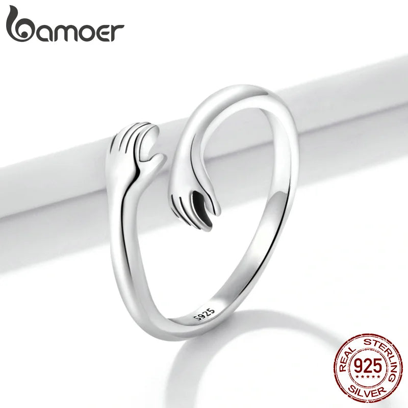 Anel Feminino BAMOER Abraço de Amor – Prata 925 Ajustável | Design de Mãos Entrelaçadas – 3 Cores Elegantes"